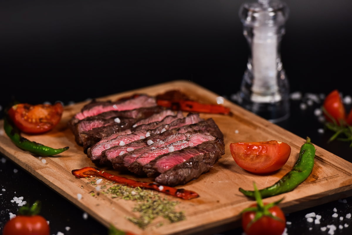 Rumpsteak mit kräftiger Kruste, Tomaten und Chili auf einem Teller angerichtet