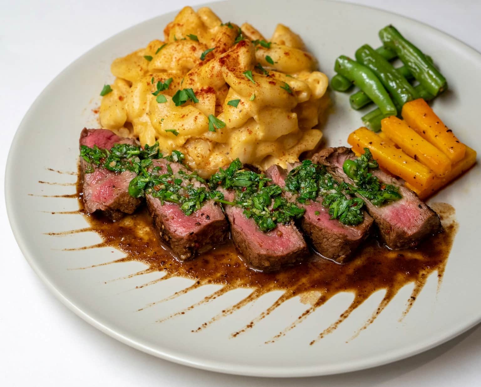 Gegrilltes Steak mit grüner Chimichurri-Sauce auf einem weißen Teller